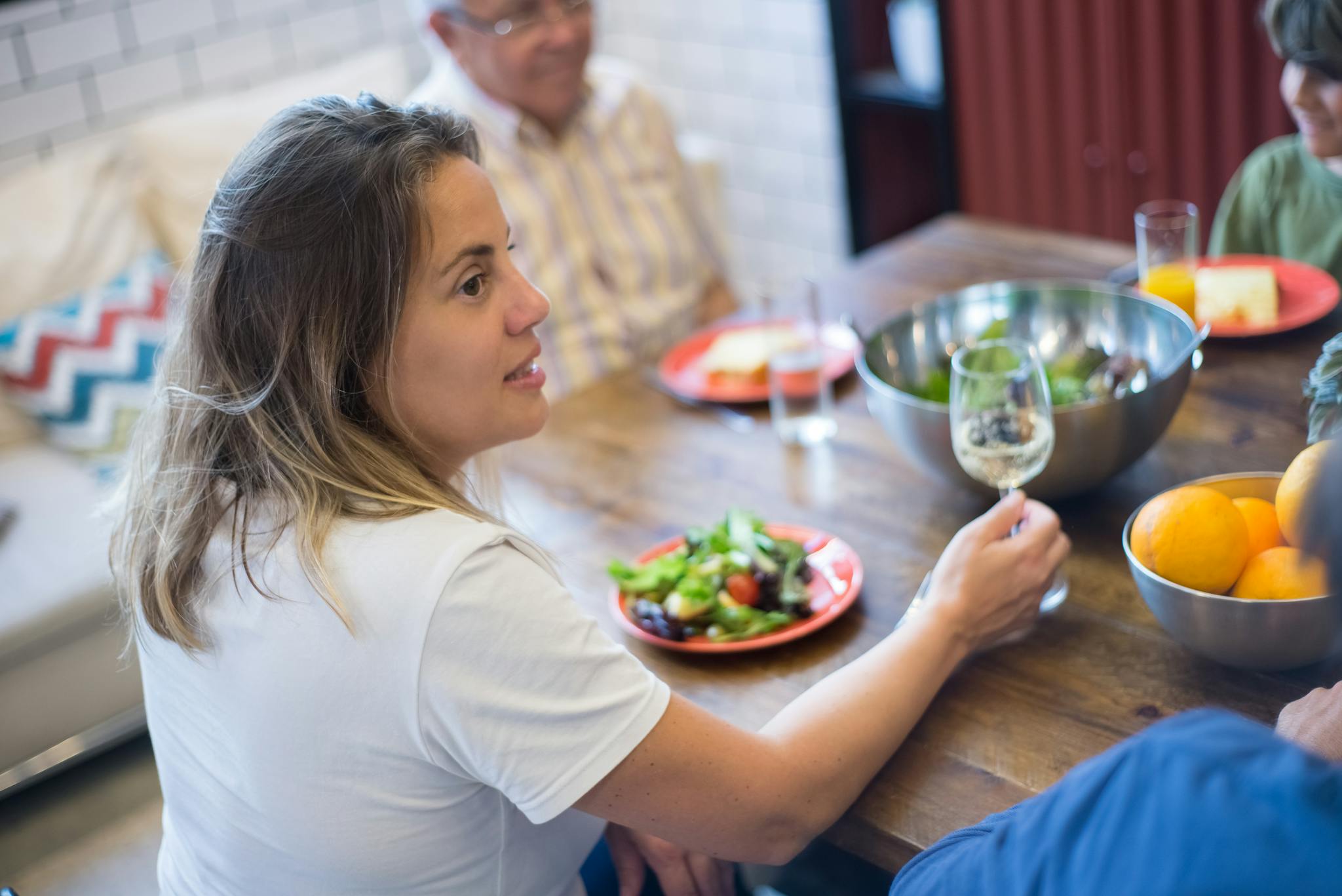 Family enjoying a casual lunch together in a modern kitchen setting, with fresh salad and wine.